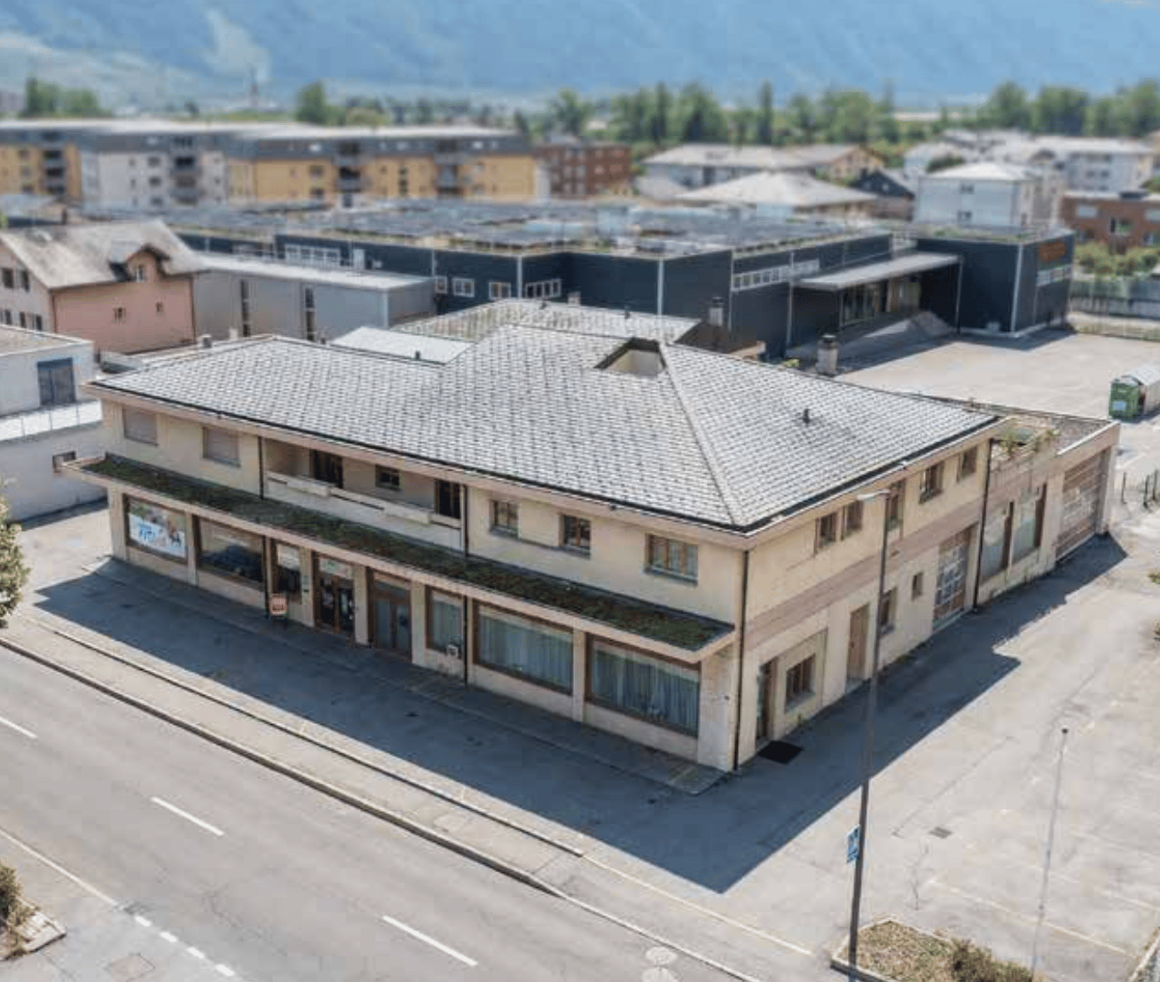 2 story building, gray roof, multiple windows, located in a city