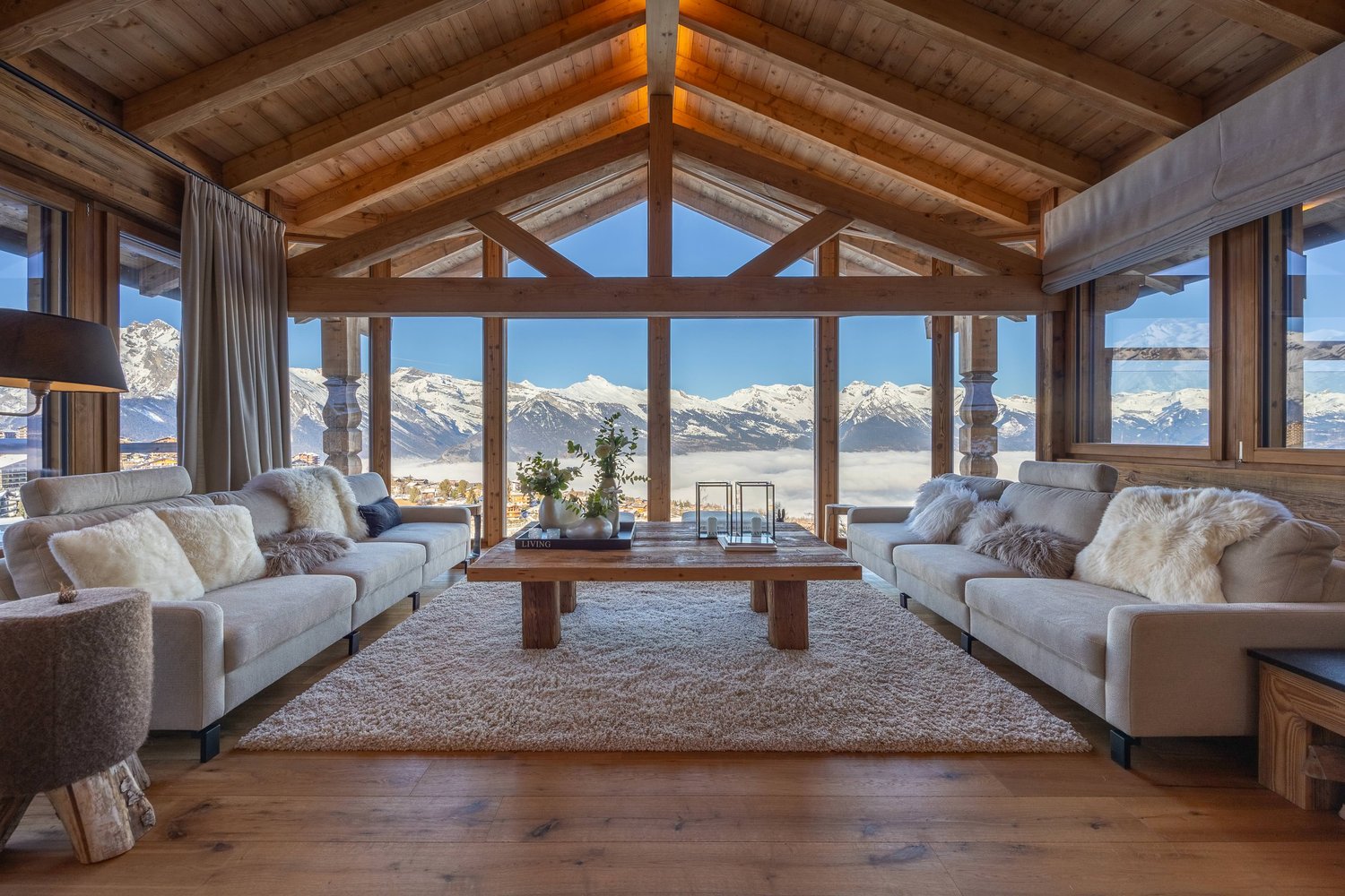 large open living space, wooden beams, large windows, sofa, coffee table, rug, table flower arrangement