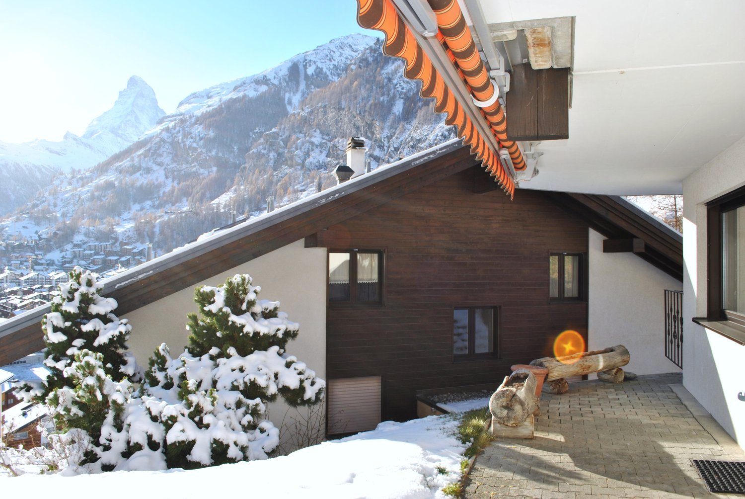 mountain house with snowy surroundings, wooden facade, two windows, pathway