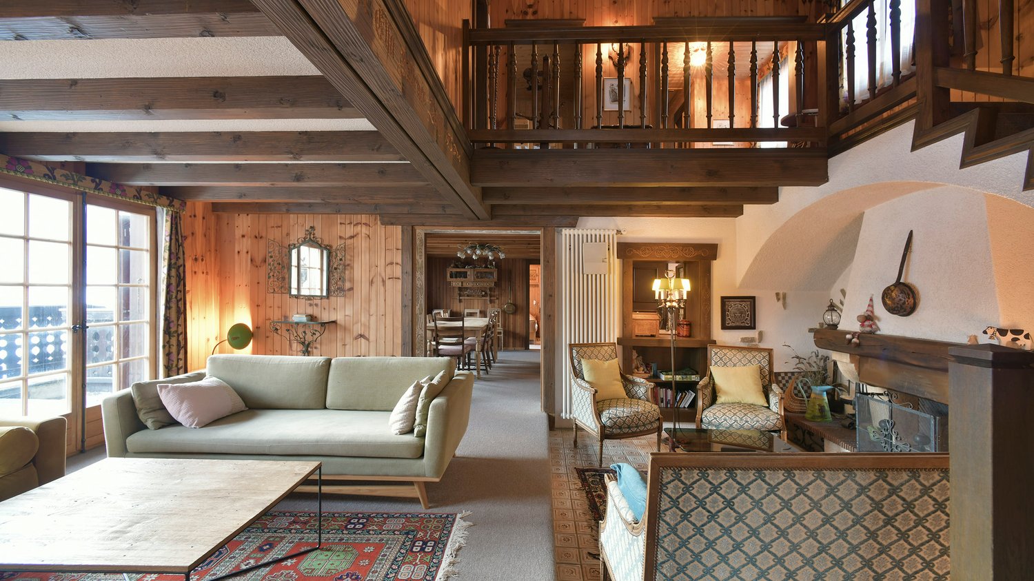 Fireplace, balcony, wooden beams, couch, chairs, table, carpet, wooden flooring