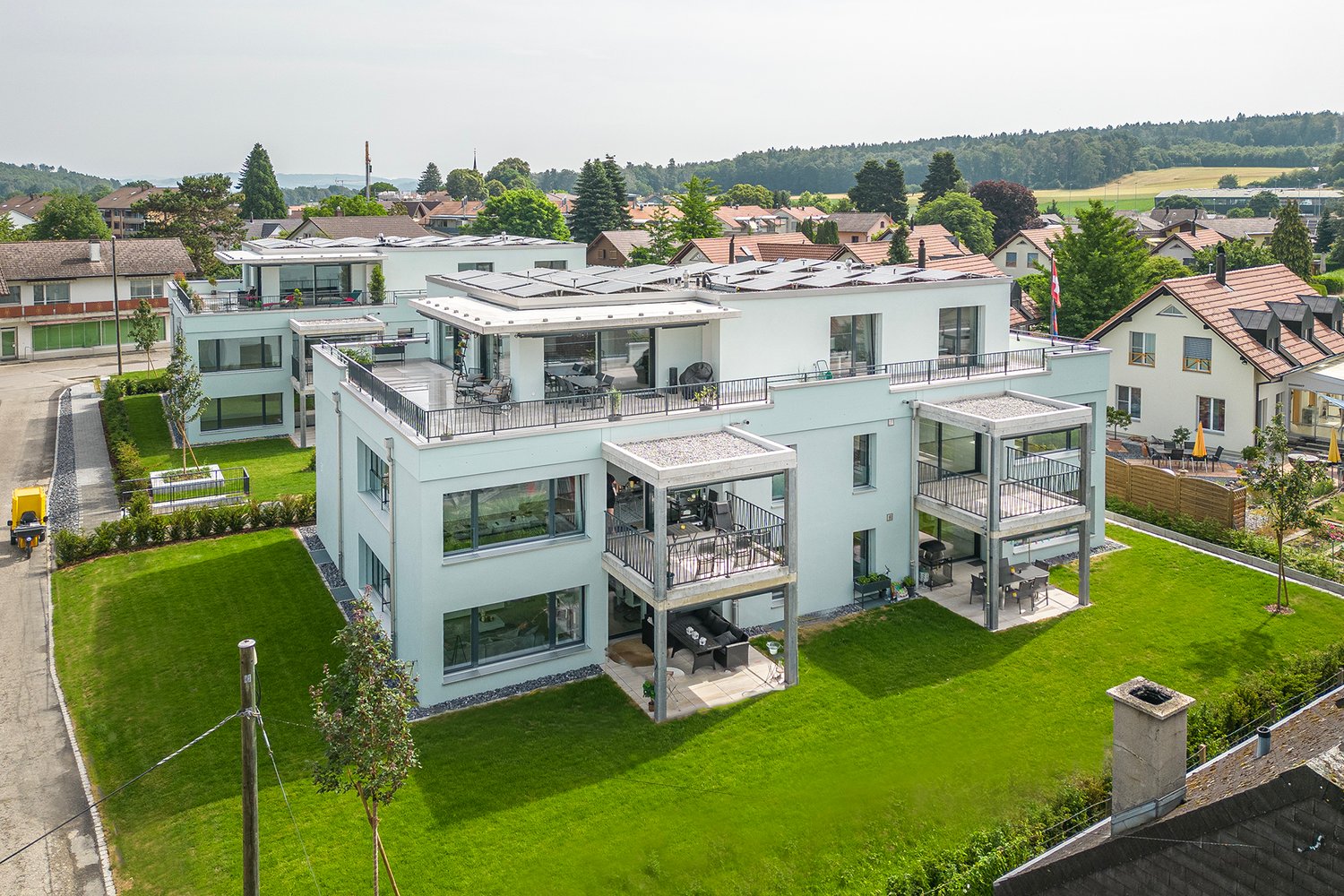 Apt complex, solar panels on roof, multiple balconies, outdoor furniture