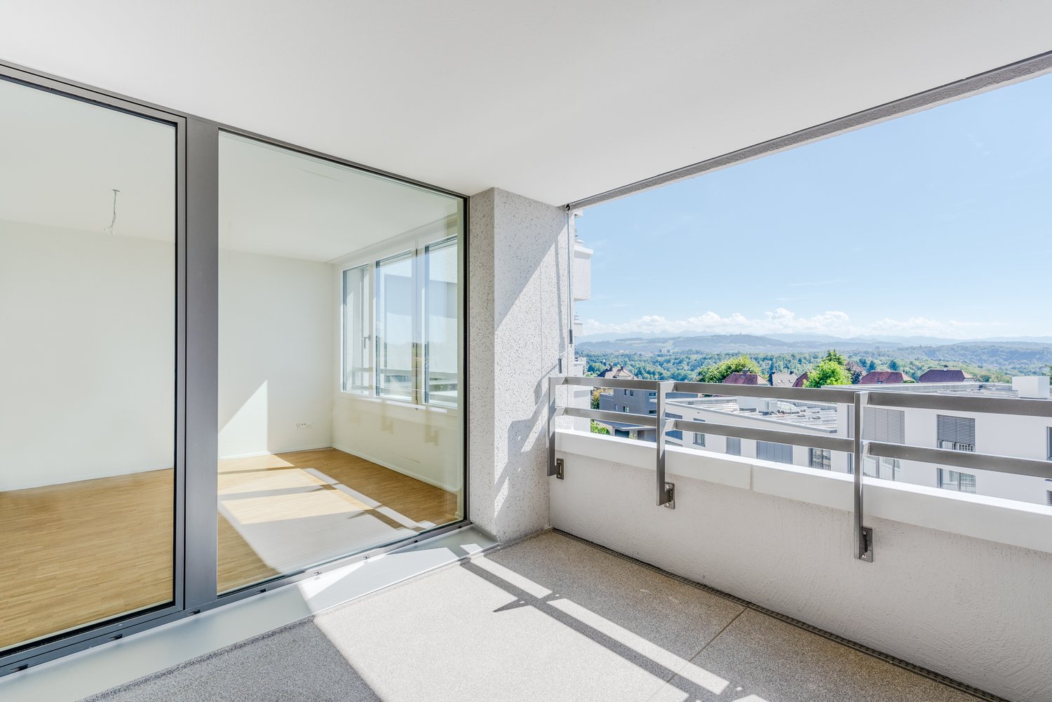 Large balcony, large sliding glass doors, wooden floor, panoramic mountain views, metal railing