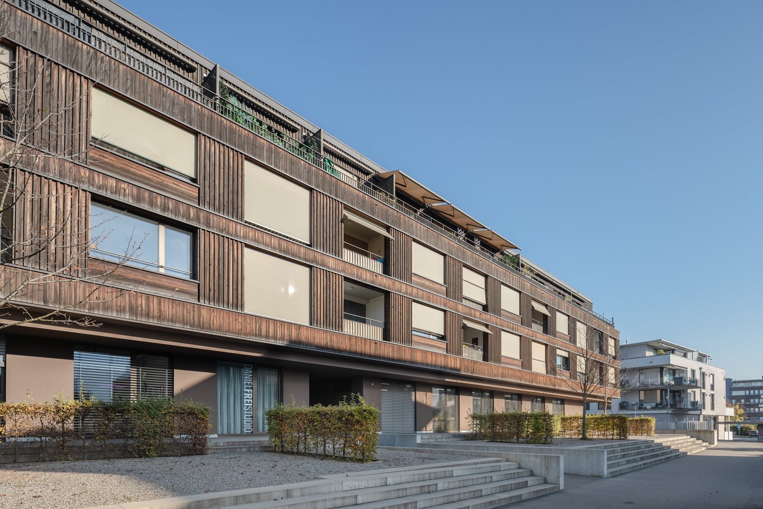 Modern design building with wood panels, balconies, and multiple windows.