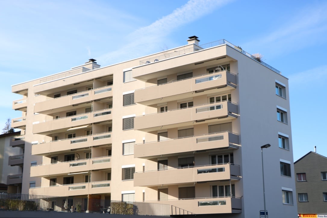 5-story apartment building, beige exterior, multiple balconies on each floor, windows with shutters
