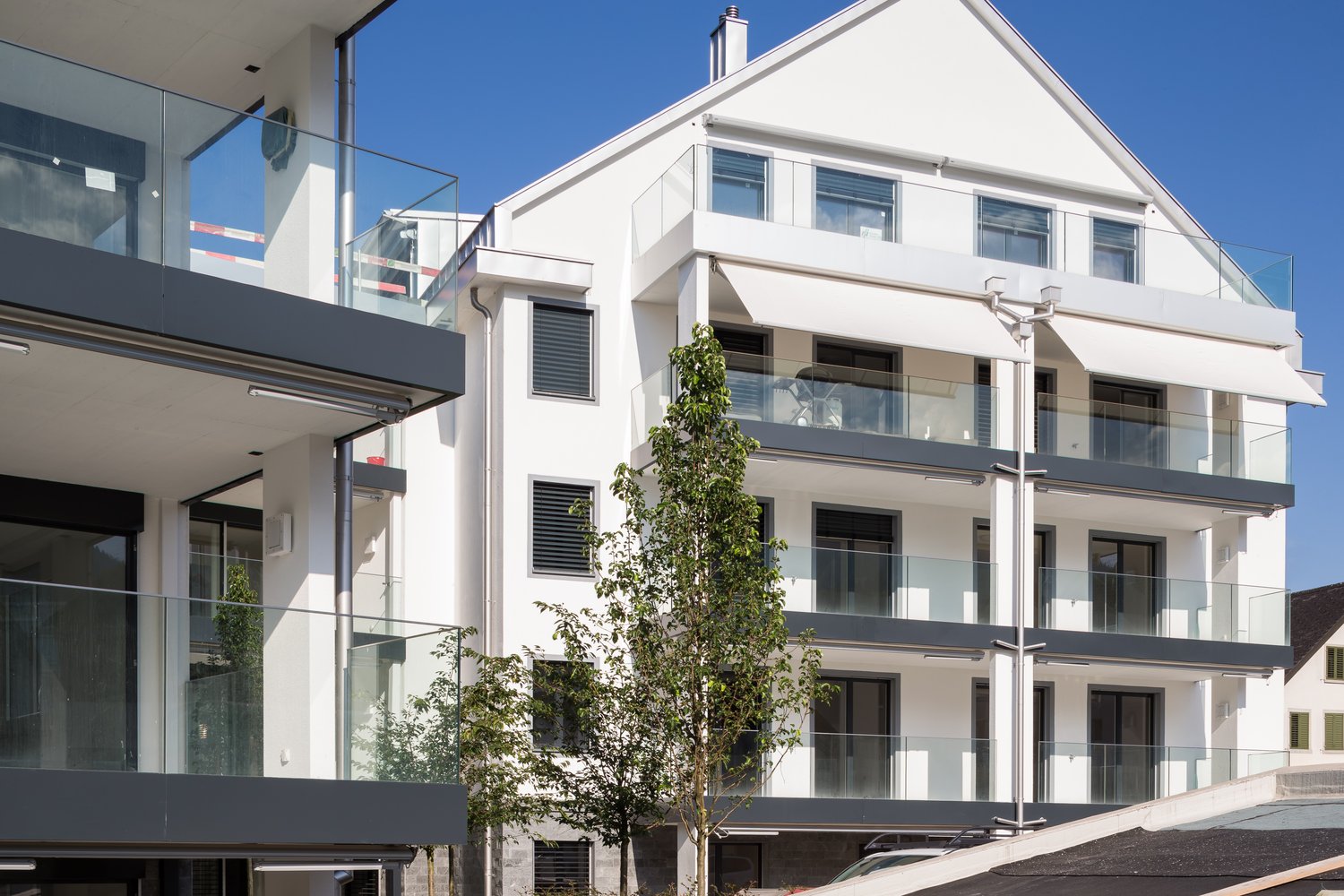 Modern white building, glass balconies, multiple floors, metal railings