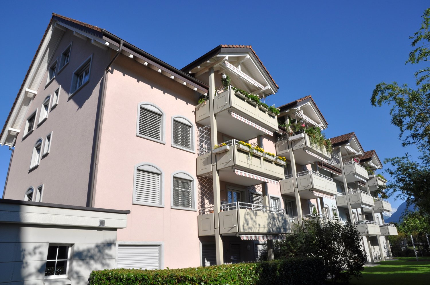 Modern pink apartment building with balconies, multiple floors, modern architecture
