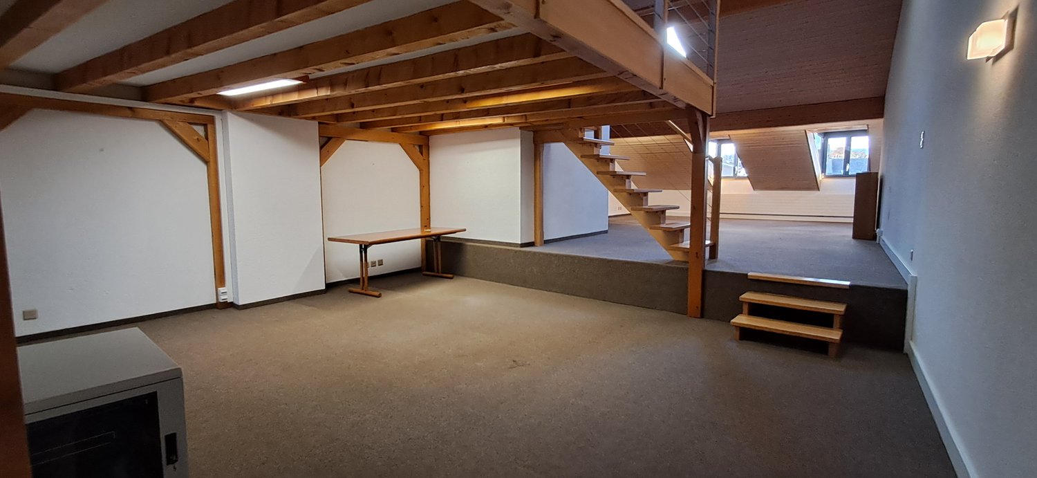 room with wooden beams, wooden table, white walls, wooden stairs
