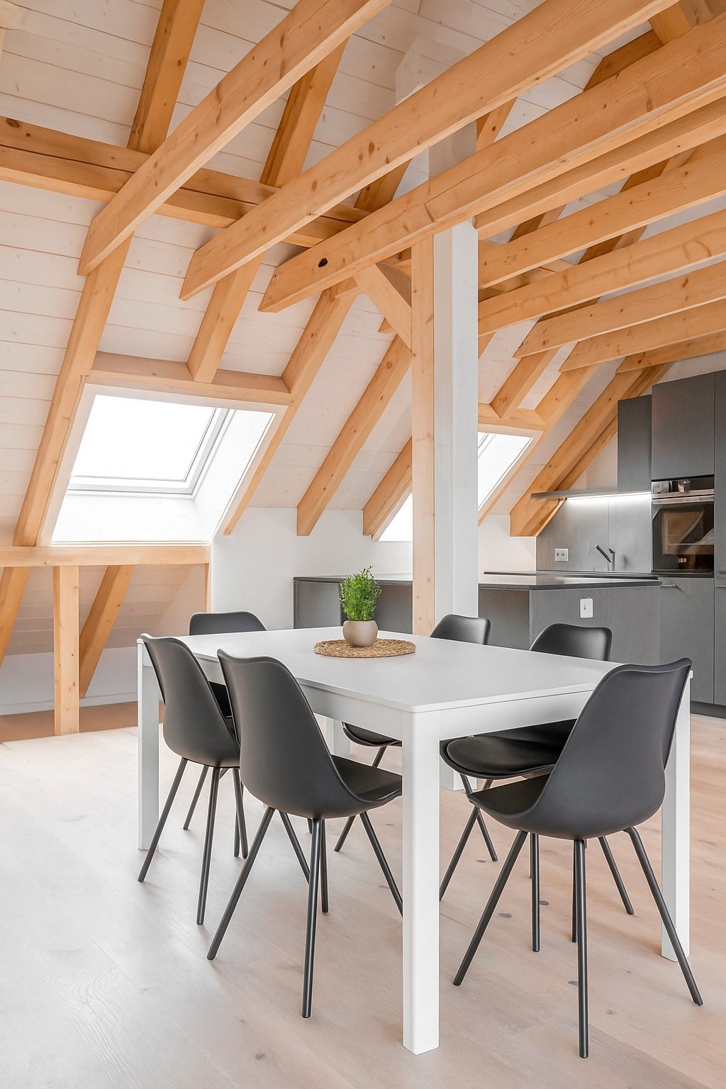 Dining area with white table and chairs, kitchen area with oven, wooden ceiling beams