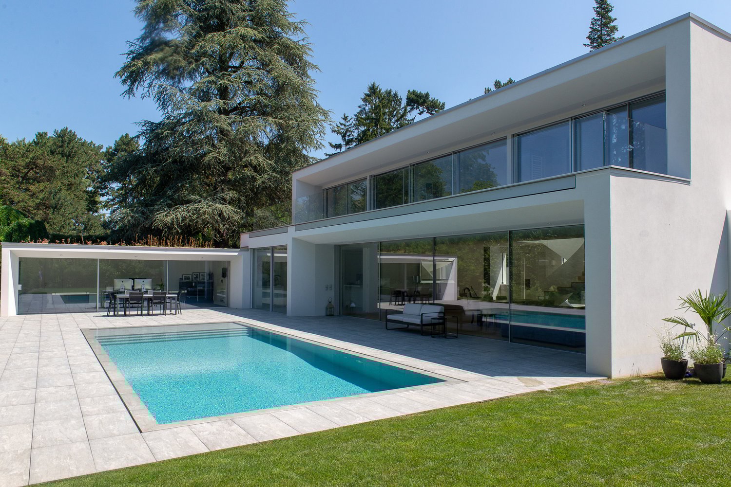 modern house, white exterior, large glass windows, outdoor swimming pool, patio, lawn