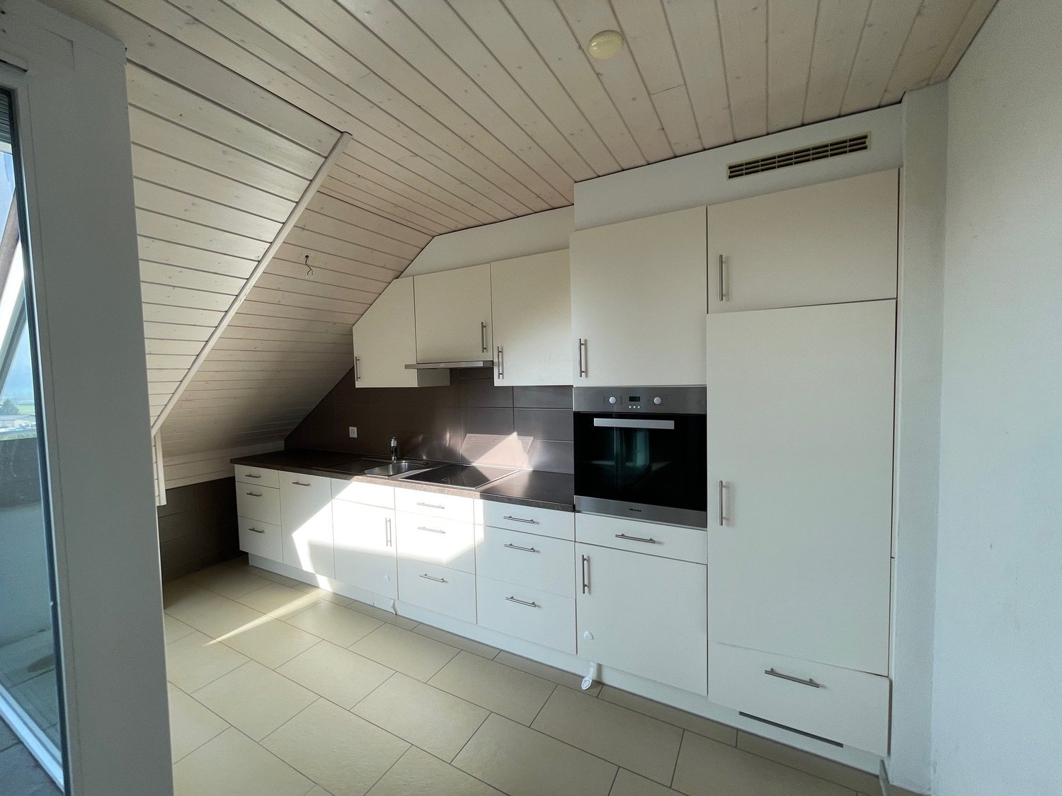 modern kitchen, tiled floor, white cabinets, black countertops, integrated oven, view through the glass door