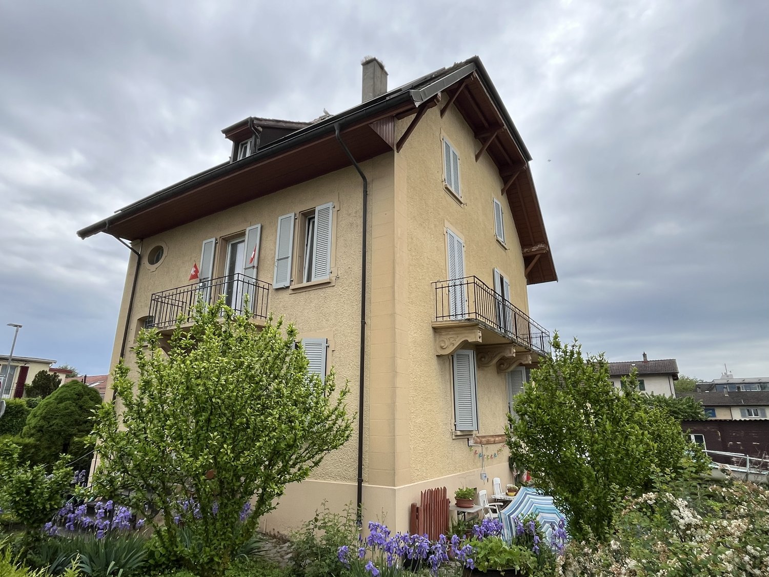 2 story house, beige paint, several windows, balcony on second floor, small front garden