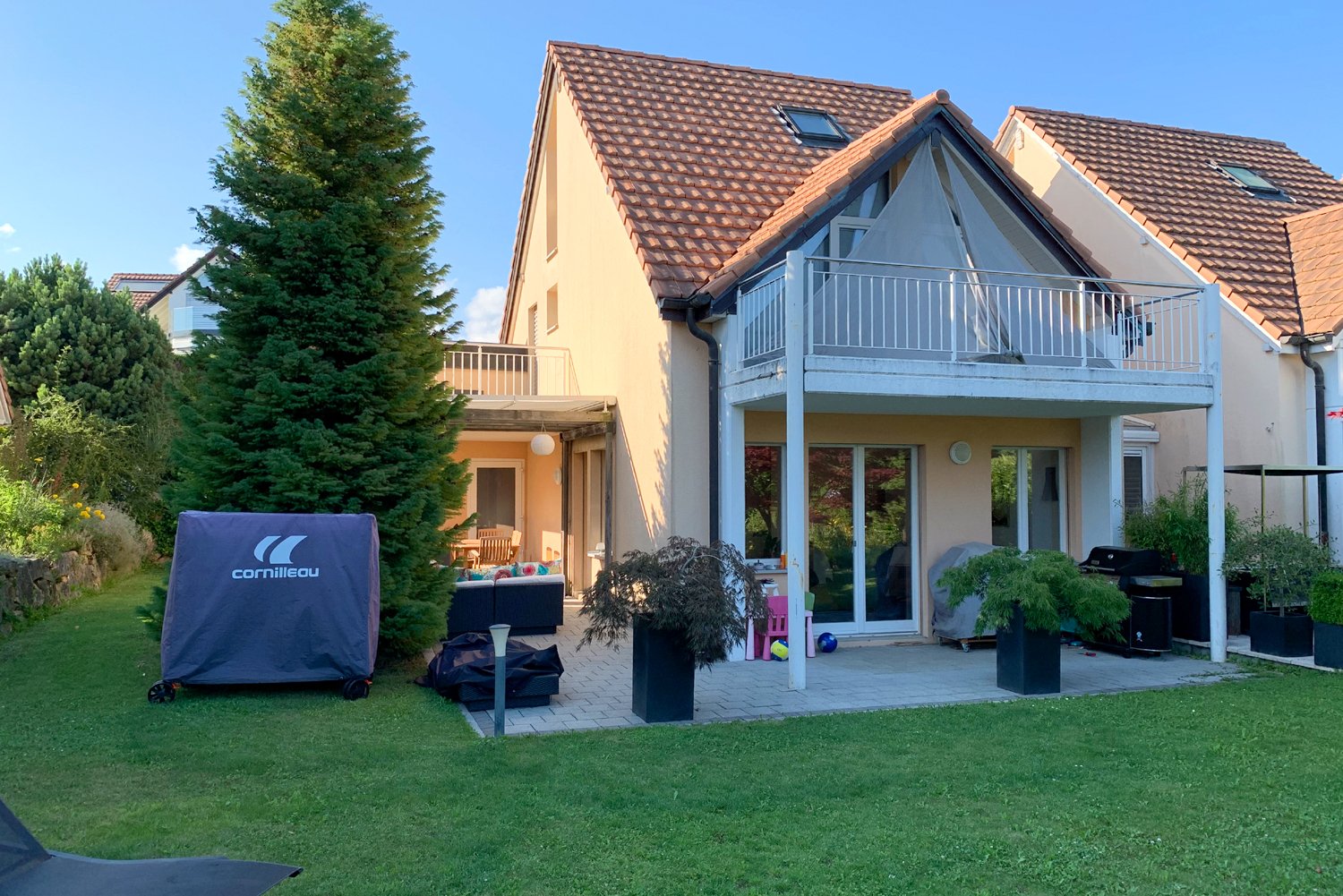 2 story house, beige paint, brown tiled roof, balcony, terrace, patio, covered entrance, garden, and trees