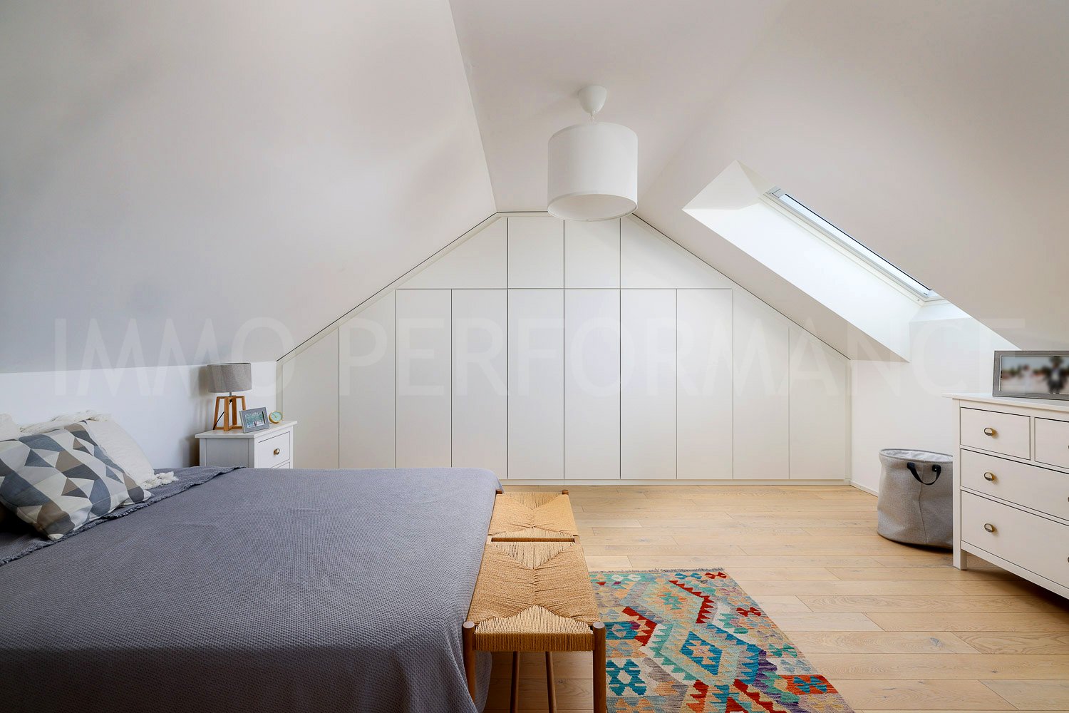 Bed with gray bedding, nightstands, built-in wardrobes, floor-to-ceiling windows, pendant light, rug, storage bin, dresser.