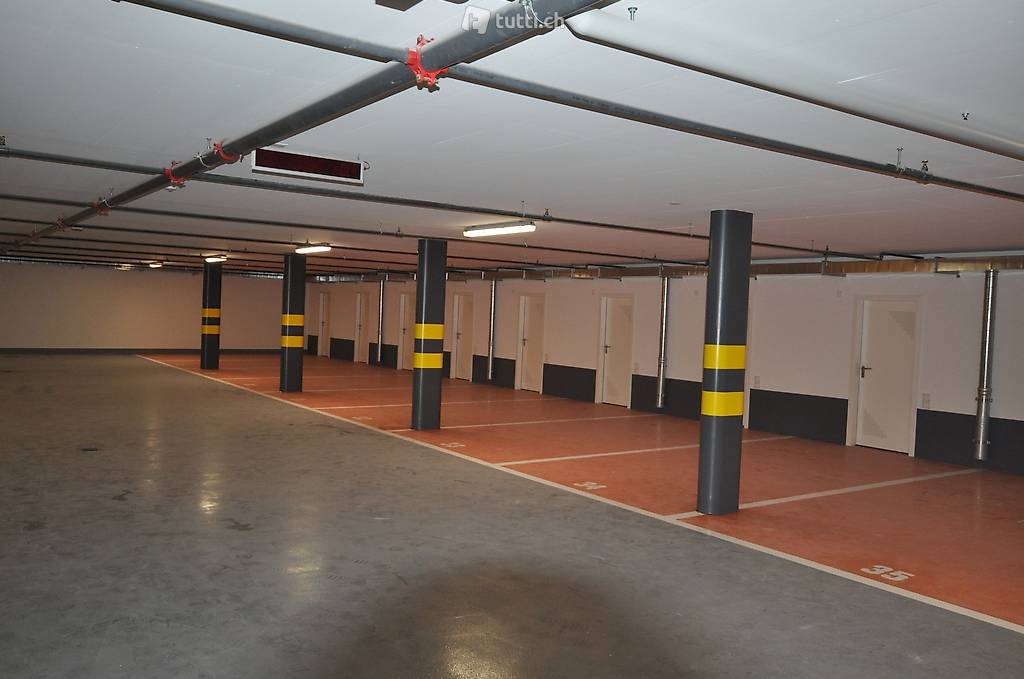 large open parking area, white walls, gray floor, columns, numbered parking spaces