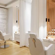 modern spa room, white walls, two white chairs, wooden floor, white curtains, white cabinets, metal fixtures