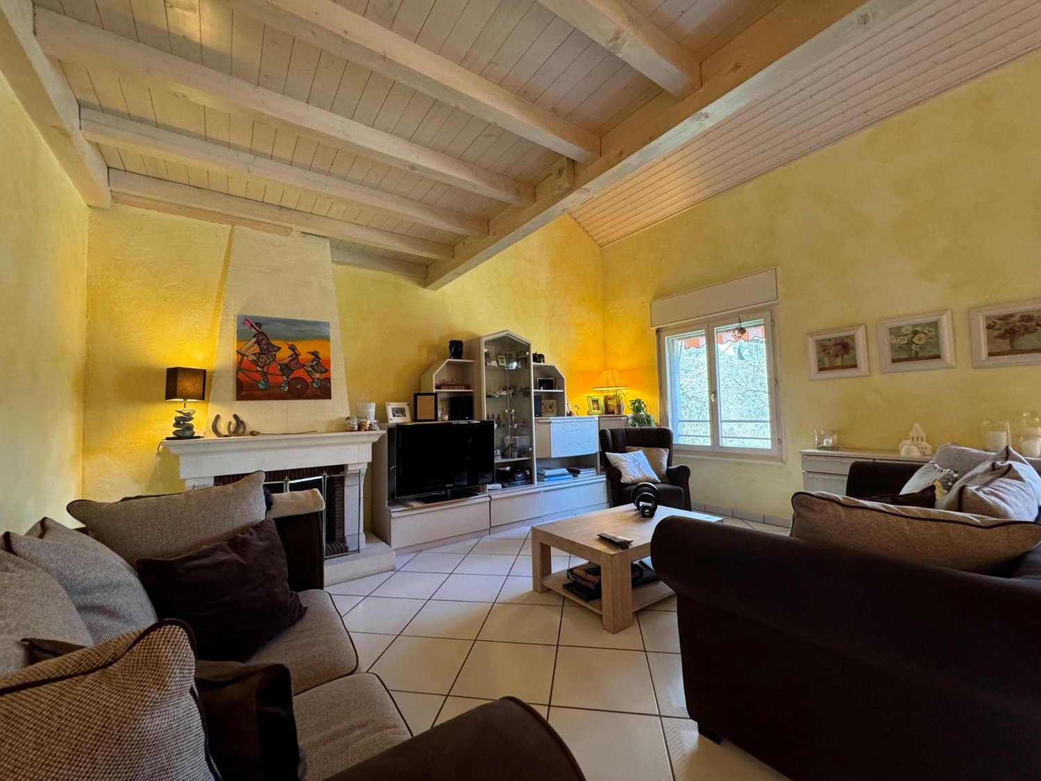 living room with yellow walls, fireplace, large windows, entertainment unit, couches, center table, lamp