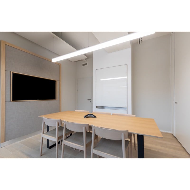 Large wooden table with chairs, white walls, TV screen, modern lighting fixtures