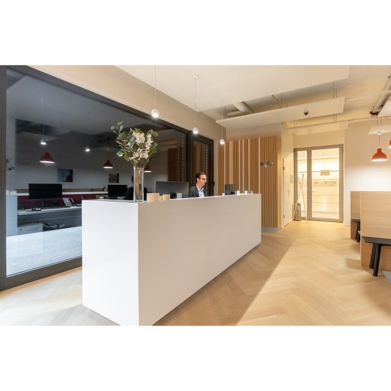 Lobby with reception desk, flowers in vase, monitor, glass partition, bench, wooden floor, LED lights
