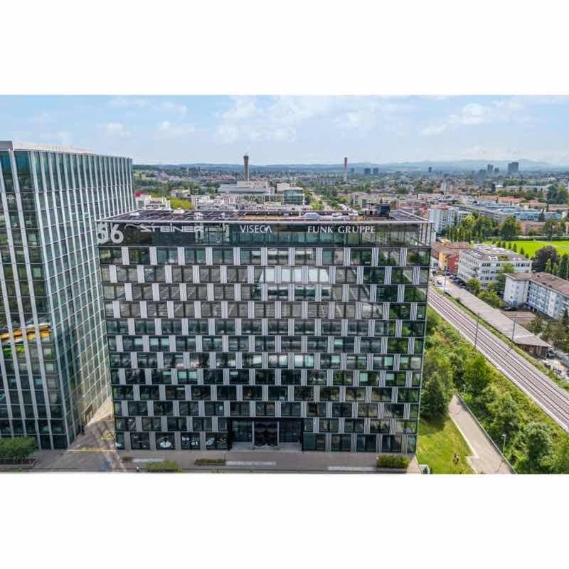 Glass exterior office building, 4th floor, modern architecture, located near a railroad, surrounded by trees and plants