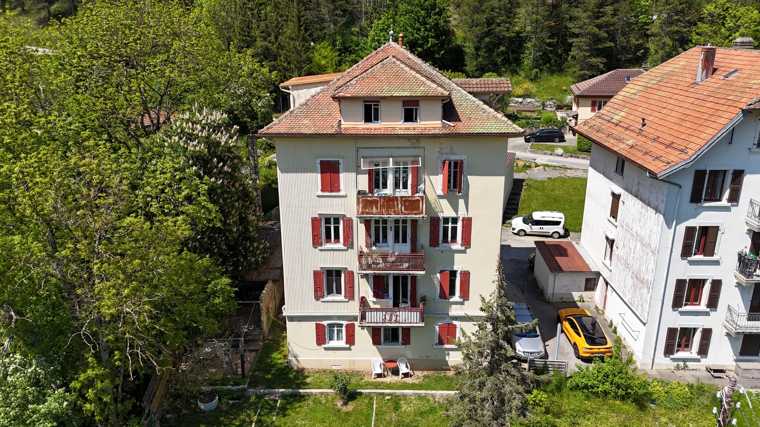 3-story house, beige paint, red shutters, 3 balconies, 3 cars parked