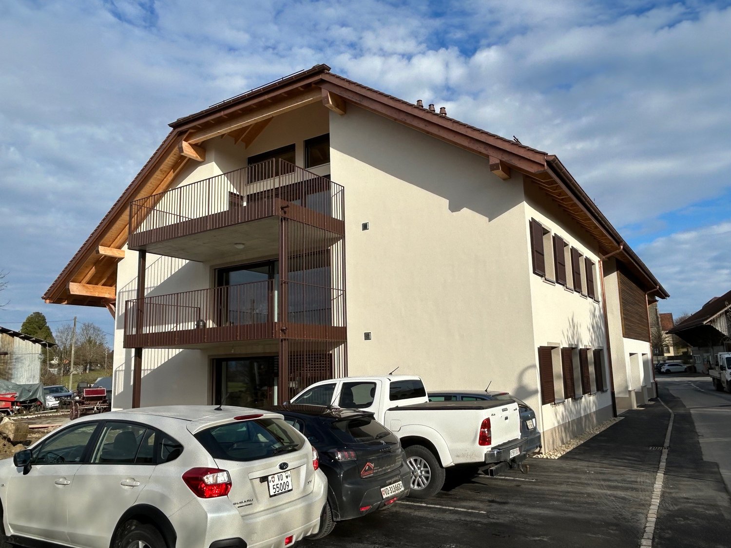 two-story house, cream colored walls, brown roof, balconies, parked cars