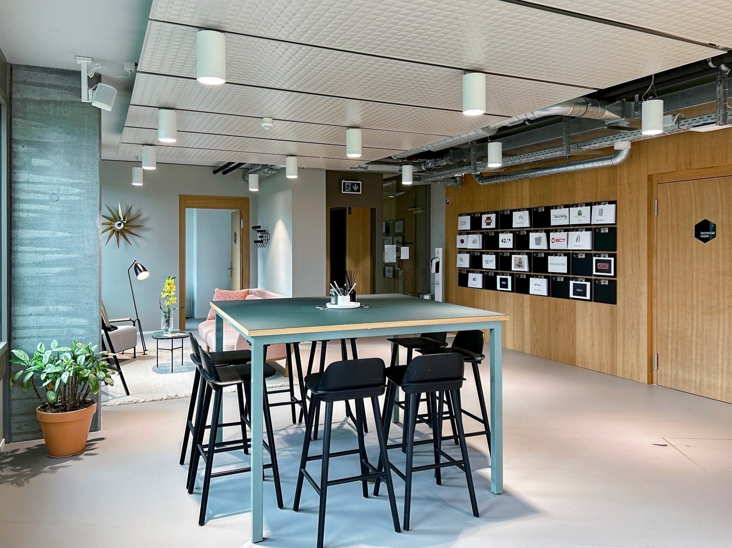 Central dining table, seating for 6, wood and metal decor, modern lighting, framed prints on wall