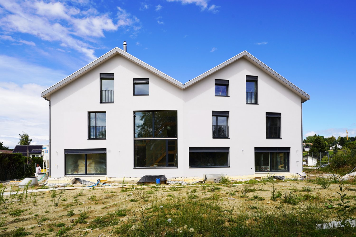 modern white house, large windows, raised ground floor, construction site in front