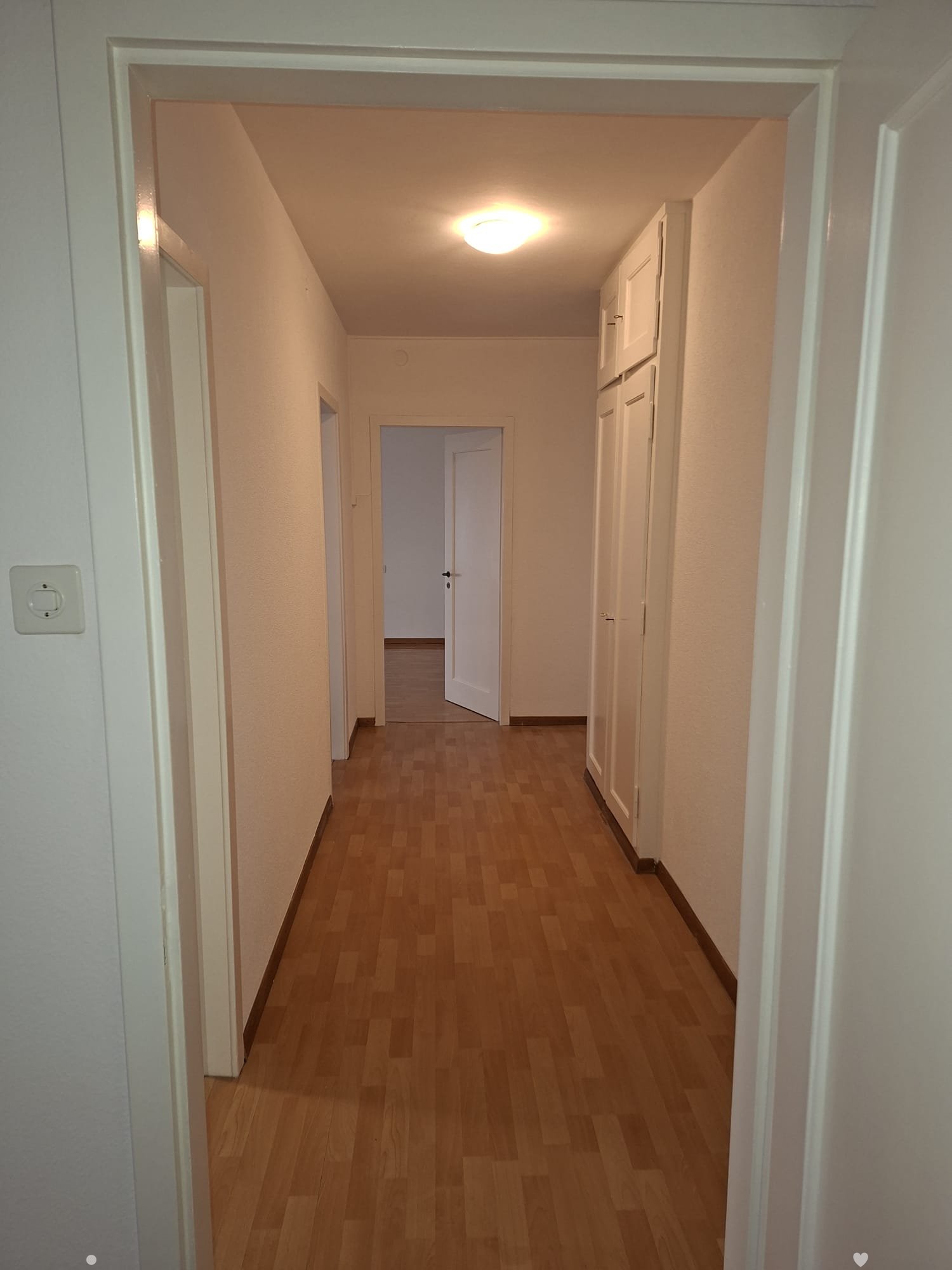 wooden floor, white walls, entrance, doors to rooms, bright lighting