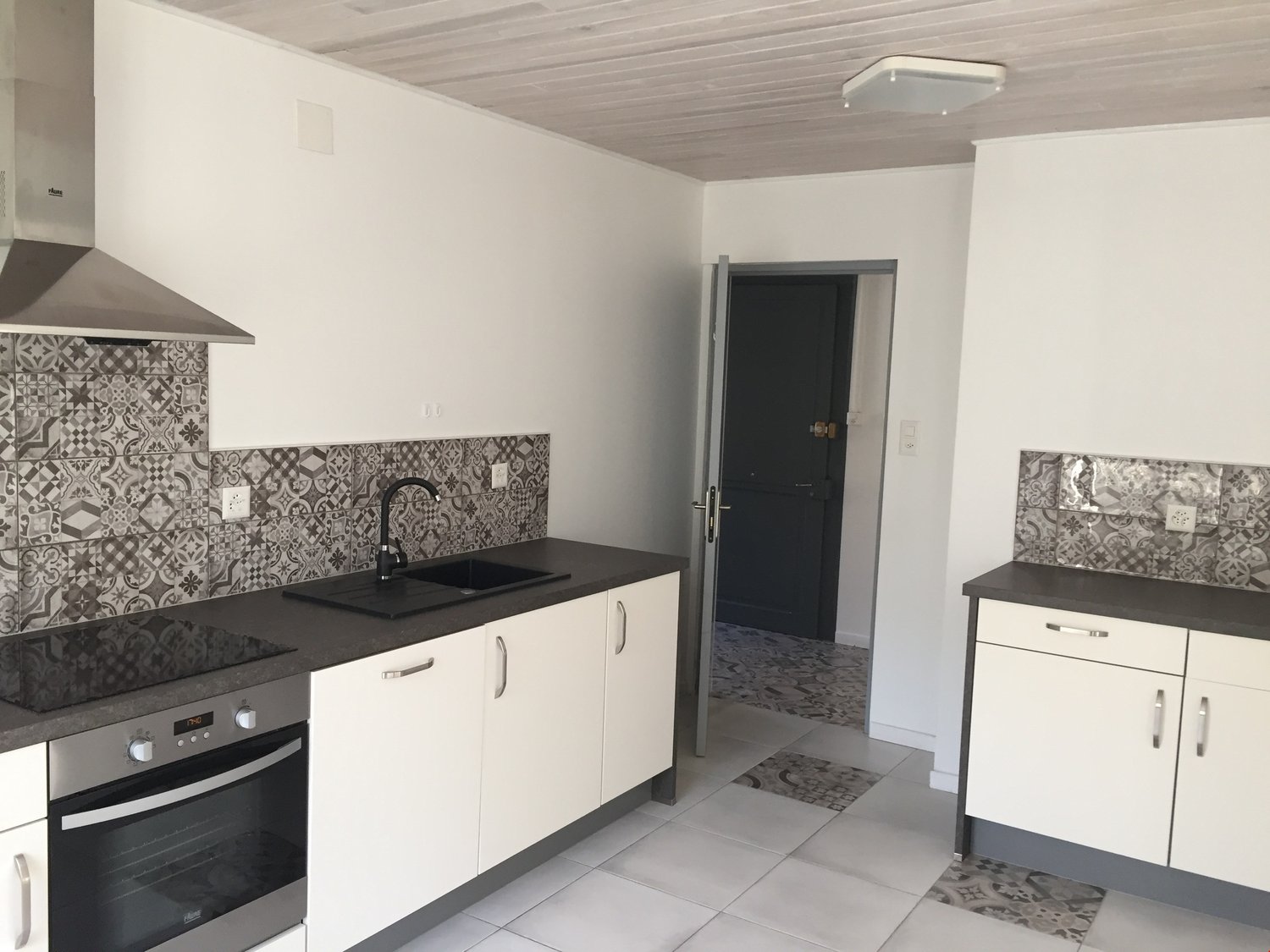 modern kitchen with black countertops, white cabinets, tiled floor, gas stove, modern sink with faucet, white walls, tile backsplash