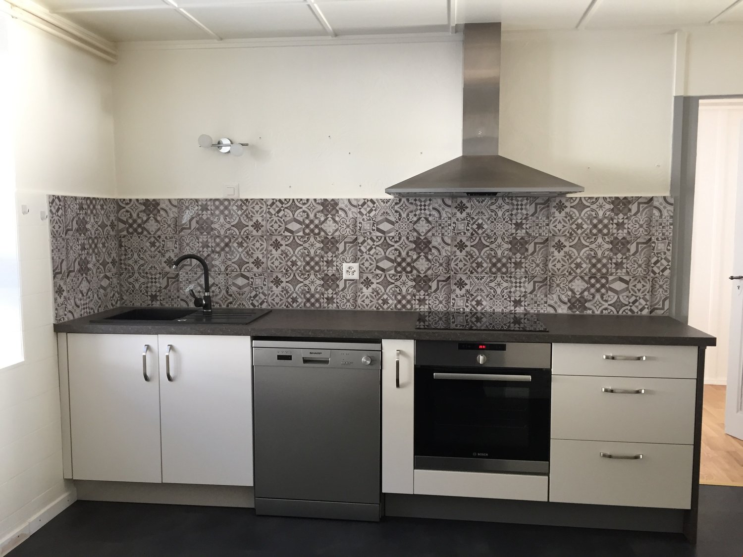 stainless steel appliances, white cabinets, granite countertops, black sink, tile backsplash