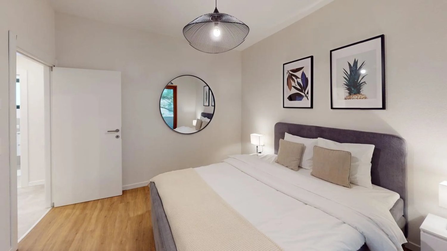 Double bed, white bedding, pillows, wall mirror, lamp, wall paintings, wooden floor