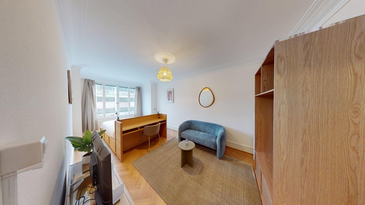 study room with desk and chair, couch, round table, carpet, lamp, television, potted plant, mirror, picture frame, window with curtains