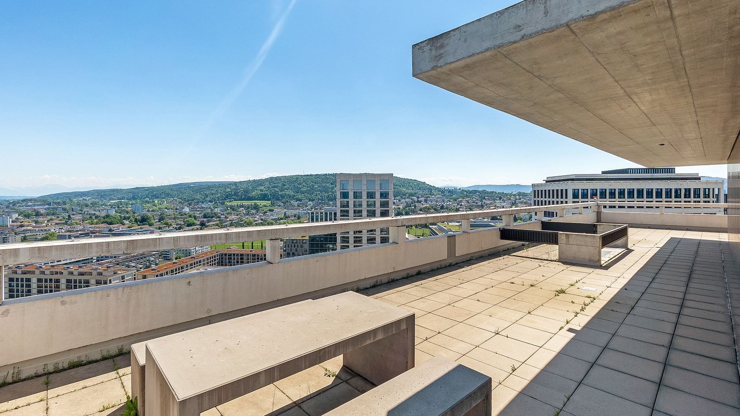rooftop terrace with a view of the city, paved floor, concrete benches