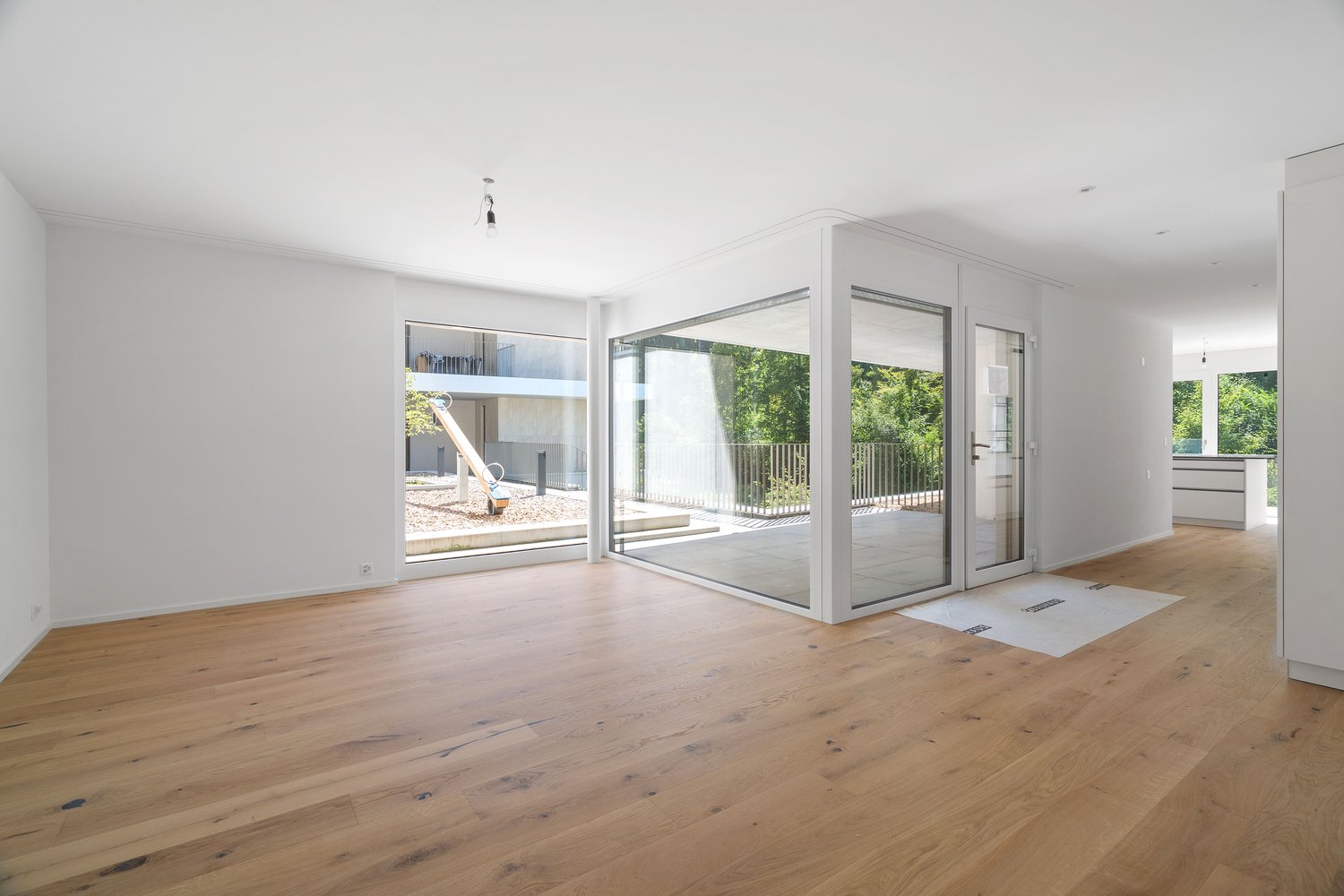 Large sliding glass doors to balcony, white walls, wooden floors, sliding glass door to kitchen area, modern design