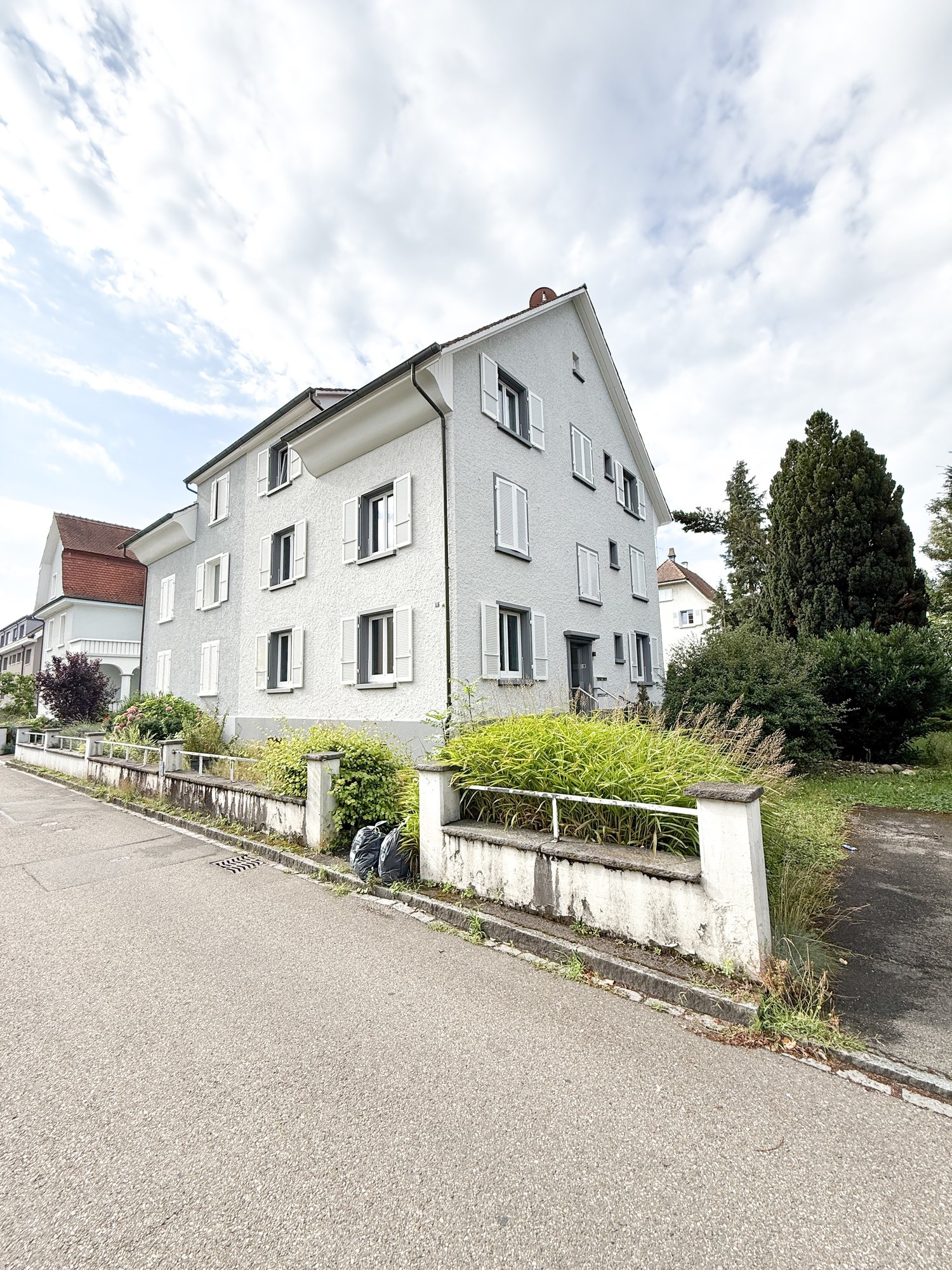 3 story house, white exterior, multiple windows, raised ground floor, side street, garden