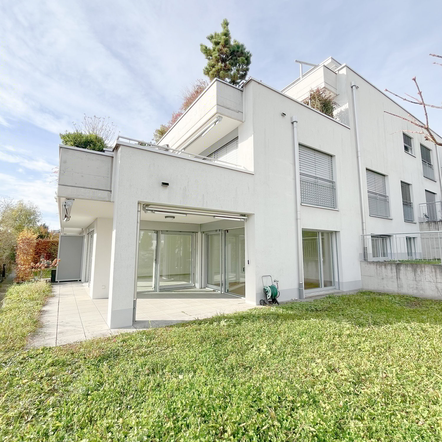 2 story house, white facade, raised ground floor, garden, glass doors, tiled pavement