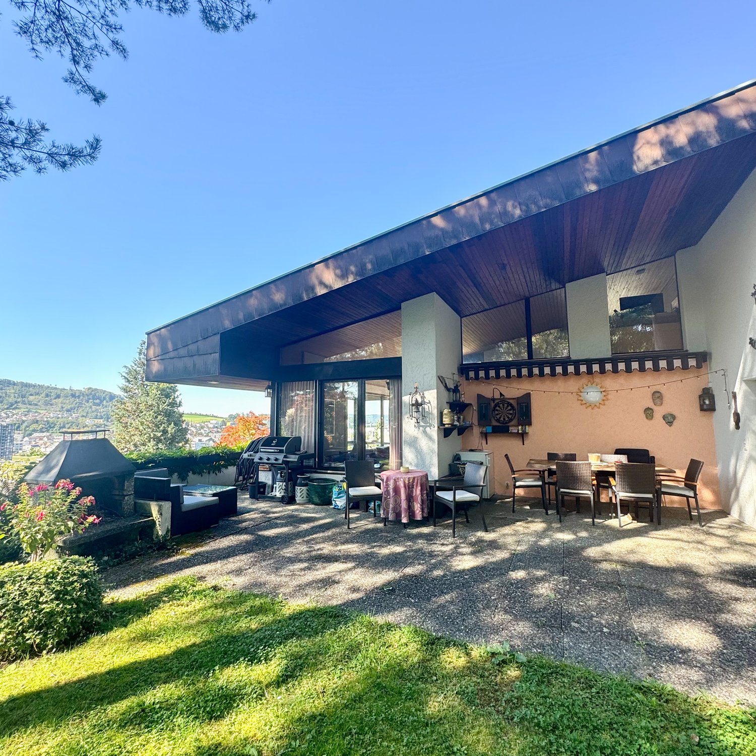 Modern building with outdoor seating area, covered terrace, barbecue, and garden. Located near city.