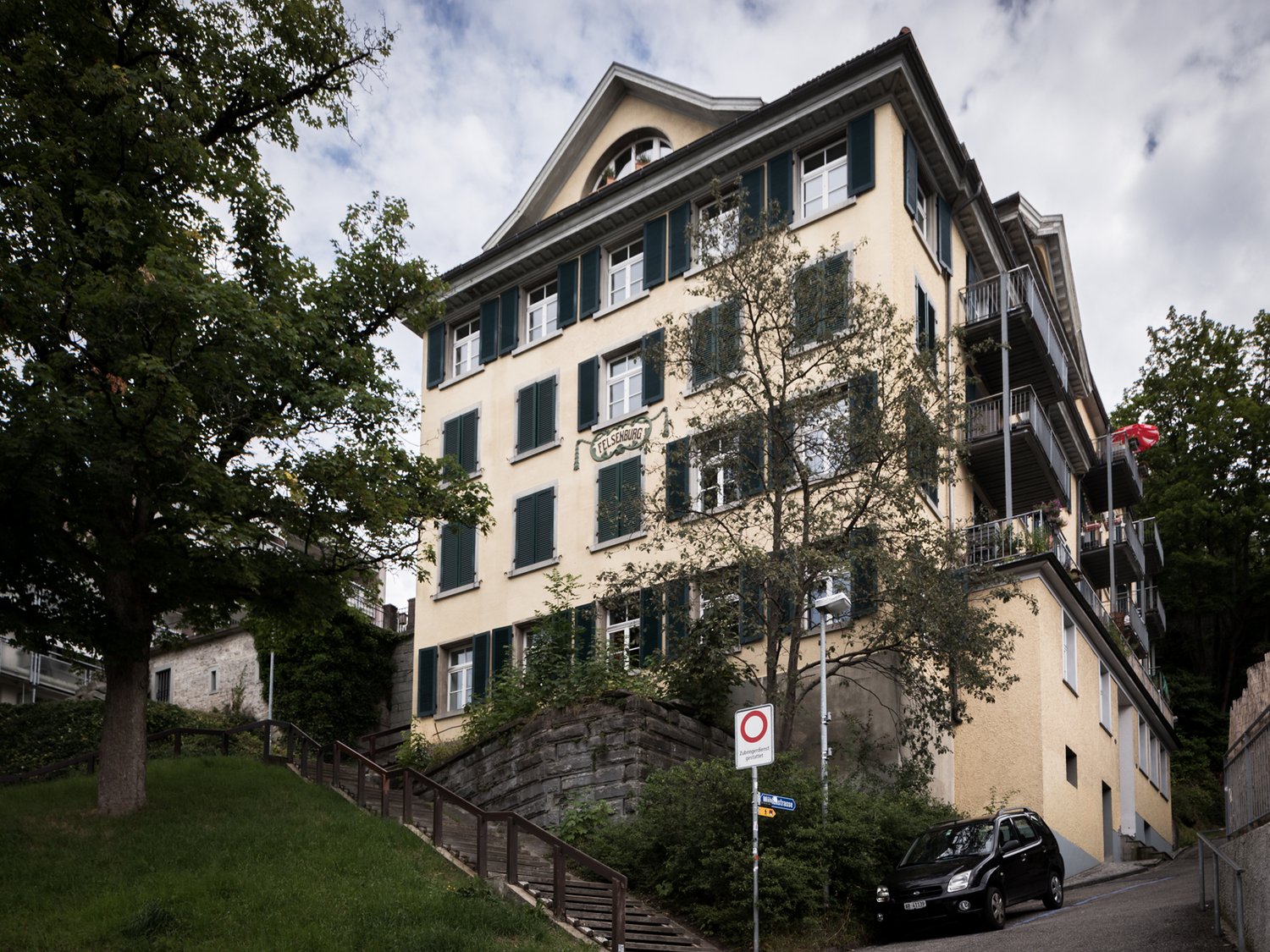 apartment building with multiple balconies, 4 stories, yellow exterior, located on a slope