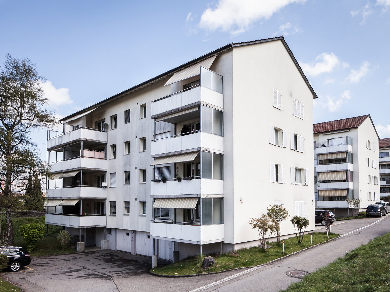 Multi-story apartment building with balconies and parking space.