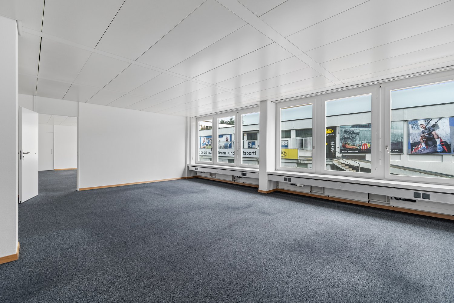 empty room, white walls, grey flooring, large windows