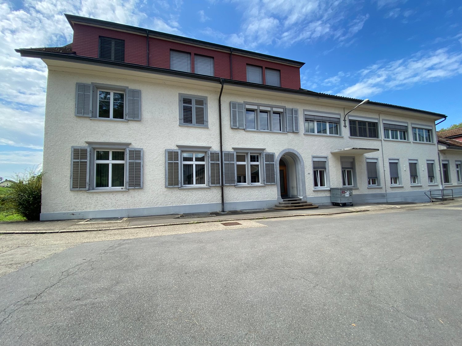 Two story house, red roof, many windows, concrete driveway, grey walls