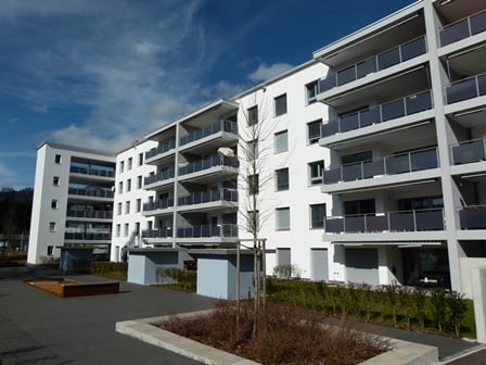 Apartment complex with multiple balconies, paved courtyard, street lamp