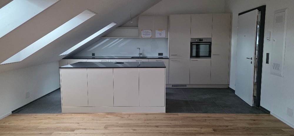kitchen in attic with skylights, white cabinets, wooden floor, black countertop, oven, sink, faucet