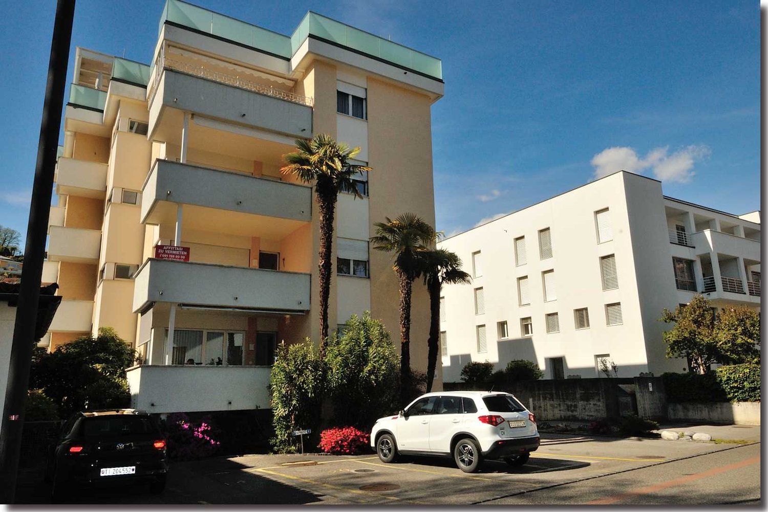 3-story building, beige and white color, balconies, car parking area