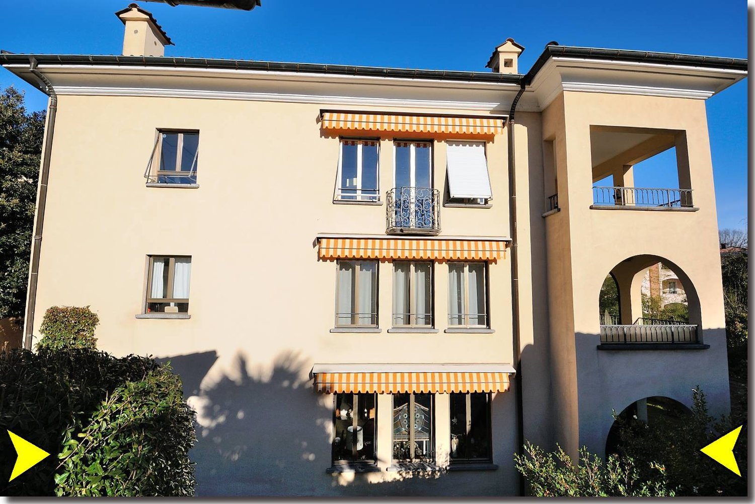 3 story building, beige exterior, glass windows, 3 balconies, archways