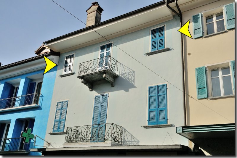 Two story house, blue and white painted walls, chimney, two balconies, windows with blue shutters