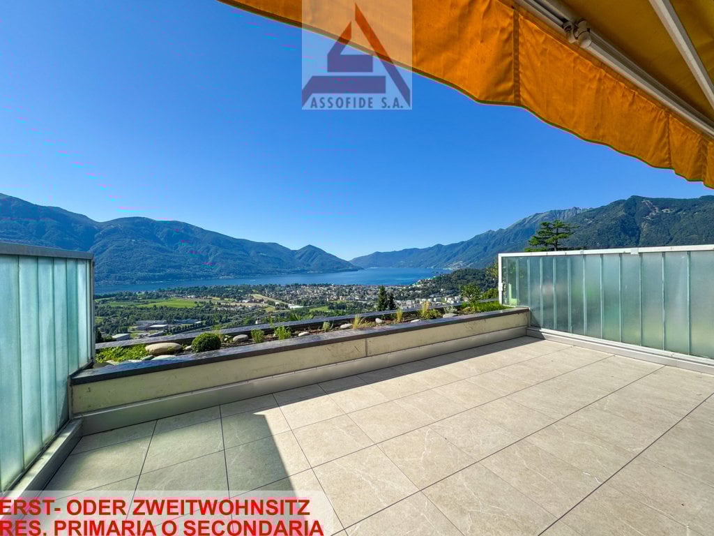 Terrace with tiled floor, glass railing, view of mountains and lake
