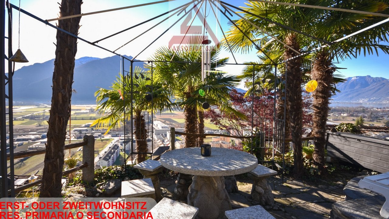 Outdoor terrace with seating area, table, pergola, palm trees, mountainous background, scenic landscape