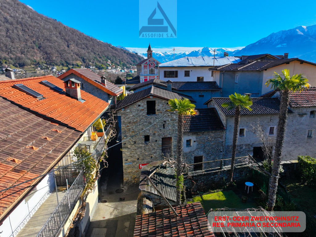 Stone buildings, red roofs, balconies, mountains in the background