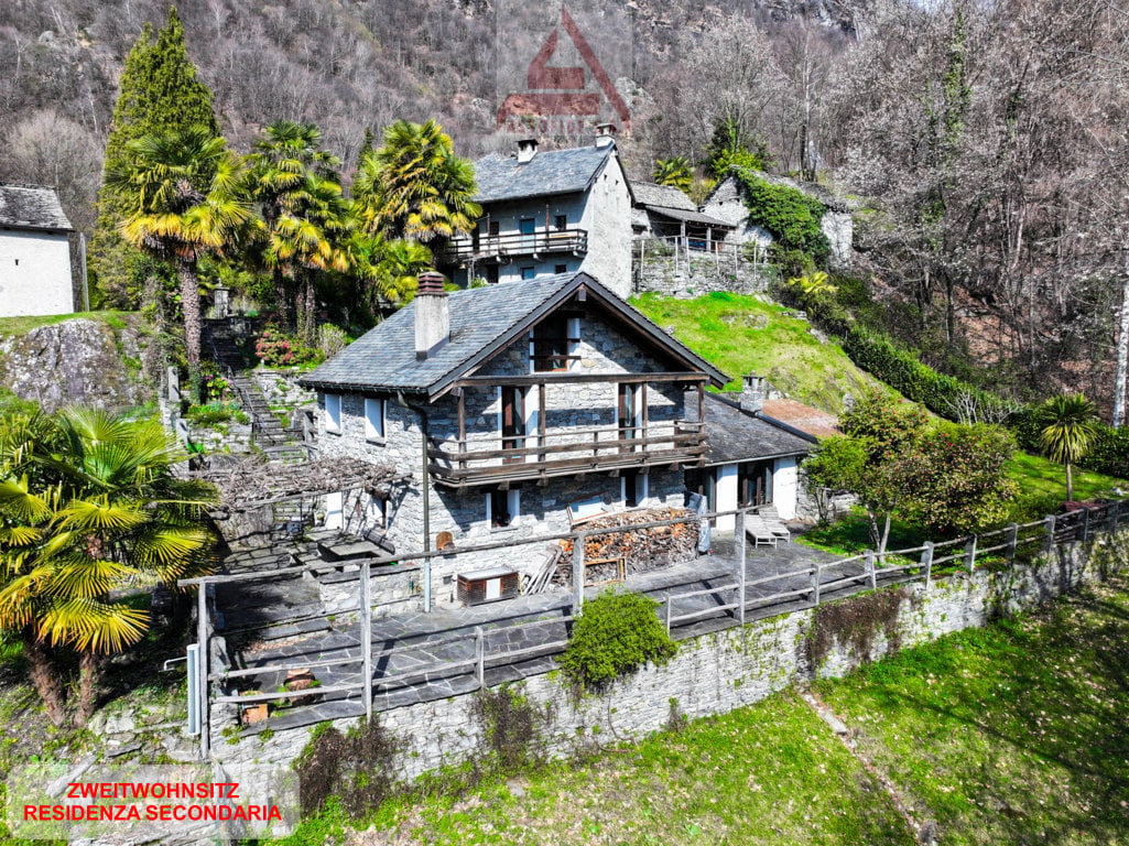 Stone house, multiple levels, wooden balcony, surrounded by trees, mountain view
